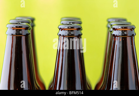 Svuotare le bottiglie di birra in righe nella parte anteriore di un luminoso sfondo verde Foto Stock
