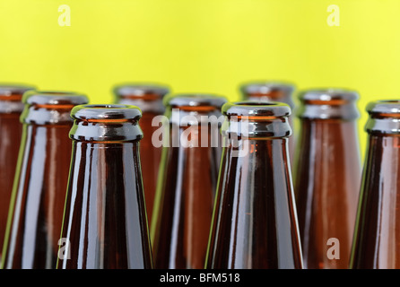 Svuotare le bottiglie di birra in righe diagonali nella parte anteriore di un luminoso sfondo verde Foto Stock