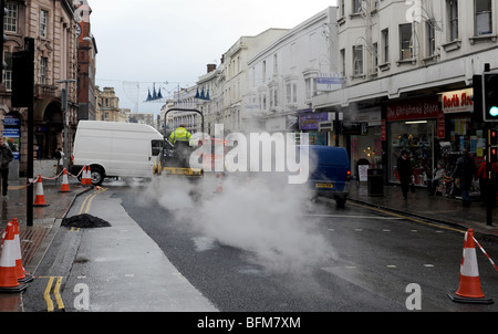 Vapore sorge come operai il relè di una superficie stradale con asfalto nel centro città di Brighton Regno Unito Foto Stock