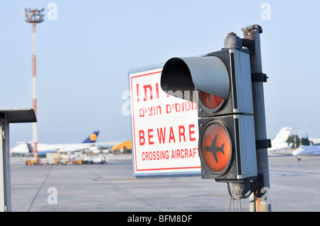 Israele, Ben-Gurion international airport. Luce di traffico e segno di avvertimento, attenzione attraversamento di velivoli in ebraico e in inglese Foto Stock