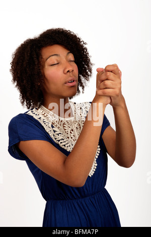 Giovani afro-caraibica donna stringendo le mani insieme come se fosse pregare o cantare un brano del vangelo Foto Stock