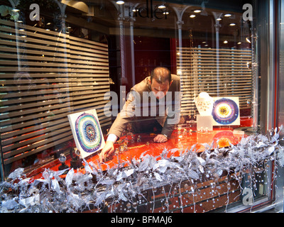 L'uomo disponendo il display di Natale nelle gioiellerie, Bond Street, Mayfair, London, England, Regno Unito Foto Stock