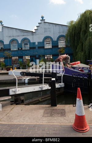 Un uomo su una chiatta che l'apertura del cancello passando attraverso Hawley Lock sul Regent's Canal, Londra Foto Stock