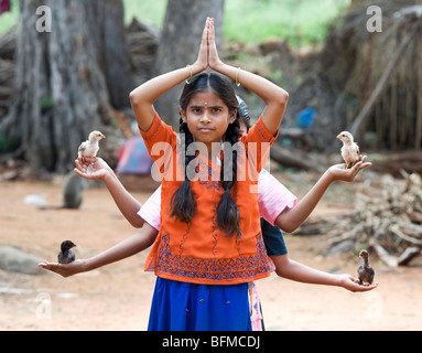 Giovani ragazze indiano con pulcini nel palmo della loro mano nella classica sei armati dea Indù postura. Nallaguttapalli, Andhra Pradesh, India Foto Stock