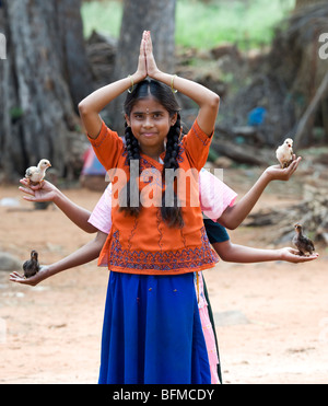 Giovani ragazze indiano con pulcini nel palmo della loro mano nella classica sei armati dea Indù postura. Nallaguttapalli, Andhra Pradesh, India Foto Stock