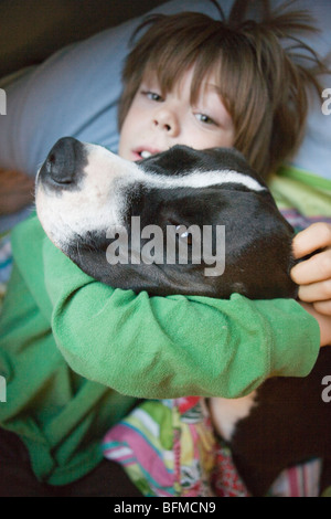 A sette anni di vecchio ragazzo risveglio tenendo il suo cane nel letto Foto Stock