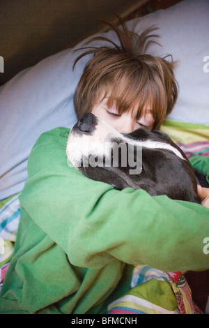 Sette anni di vecchio ragazzo che abbraccia il suo cane nel letto. Foto Stock