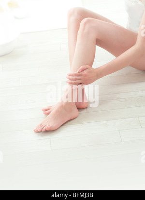 Donna di darsi un massaggio delle gambe Foto Stock