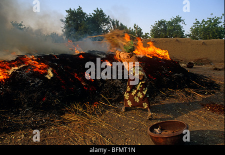 Mali, vicino a Segou, Kalabougou. Una donna aggiunge facendo accendere un fuoco in cui in ceramica - di cui il paese è famoso - è cotto. Foto Stock