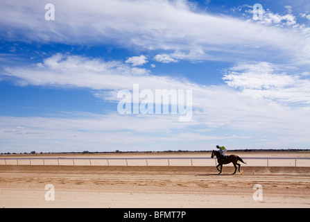 Australia, Queensland, Birdsville. Un cavallo cavaliere sul lato sporco della pista a Birdsville durante il Birdsville annuale per le gare di Coppa del. Foto Stock