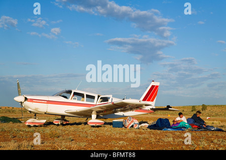 Australia, Queensland, Birdsville. Gli uomini camp accanto al loro piano su una pista di atterraggio per aerei di bush durante il Birdsville annuali gare. Foto Stock