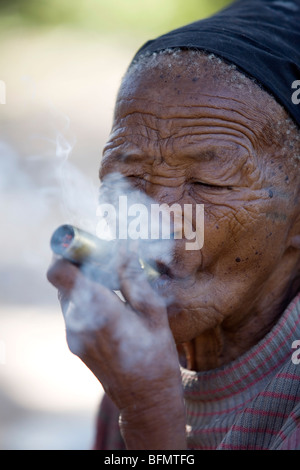 La Namibia, Bushmanland. Anziani San (Bushman) donna fumare a Nhoqma village (pronunciato //Nhoq'ma) vicino Tsumkwe Foto Stock