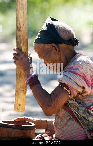 Villaggio Nhoqma (pronmounced //Nhoq'ma), Bushmanland, Namibia. Un anziano San (Bushman) donna motivi il grano per pane piatto Foto Stock