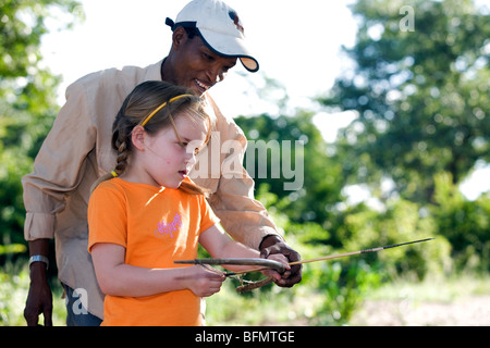 Villaggio Nhoqma, Bushmanland, Namibia .Ecoturismo progetto, una giovane ragazza impara a fuoco a San (Bushman) arco e frecce Foto Stock