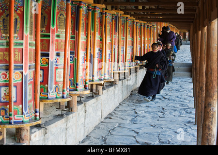 Cina, provincia di Gansu, Xiahe, Labrang monastero (1709), i pellegrini la filatura ruote della preghiera Foto Stock