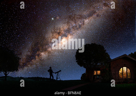 Un uomo guarda la Via Lattea al di fuori della sua casa a notte Foto Stock