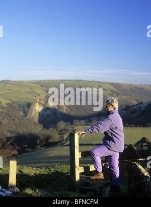 Grindon, Staffordshire, Inghilterra, Regno Unito. Senior donna walker arrampicarsi su stile che si affaccia sulla valle del collettore. Foto Stock