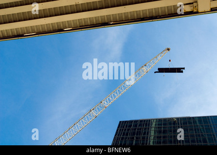 Una costruzione gru solleva canalizzazione per il tetto di un edificio nel centro di Manhattan a New York Foto Stock