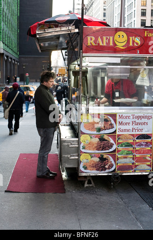 Cliente maschio attende pazientemente per suo ordine sotto il cielo nuvoloso di un giroscopio food cart su un Park Avenue South marciapiede di New York City Foto Stock