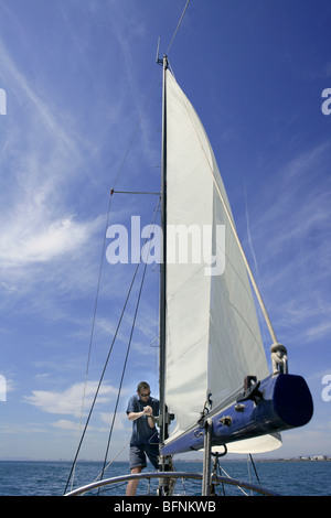 Sailor in barca a vela manovre delle vele su sunny summer blue sky Foto Stock