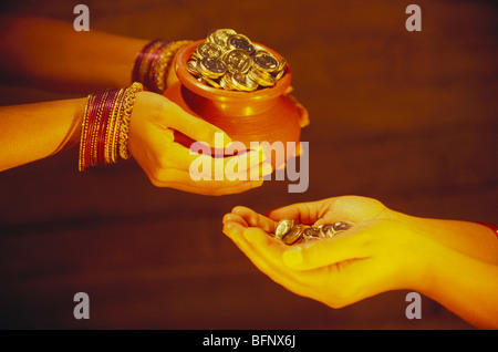 Mano che trattiene le monete pot dare ad altro Foto Stock