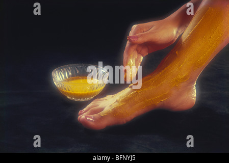 Donna applicando la curcuma incollare a piedi Foto Stock