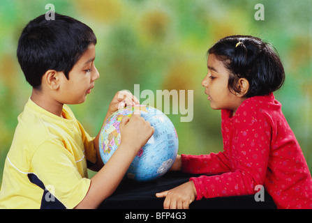 Ragazzo indiano che mostra l'India sul globo alla sorella della ragazza ; india ; asia ; MR 152 Foto Stock