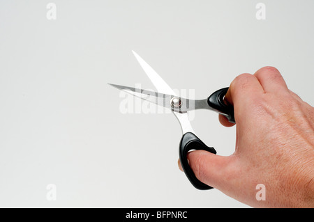 Una mano con un paio di forbici Foto Stock