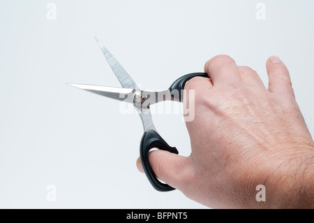 Una mano con un paio di forbici Foto Stock