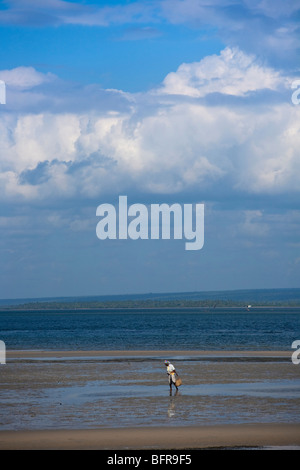 Donna che cammina lungo una spiaggia Foto Stock