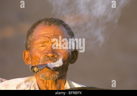 Un uomo San da Ghanzi fumare una tubazione tradizionale Foto Stock