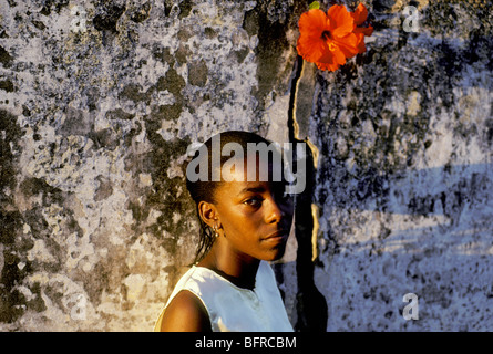 Ritratto di una giovane donna (Sandia Faquie) in piedi contro una parete di roccia con un ibisco bloom sopra la sua Foto Stock