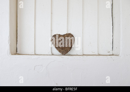 forma del cuore fatta da ramoscelli su sfondo bianco della parete Foto Stock