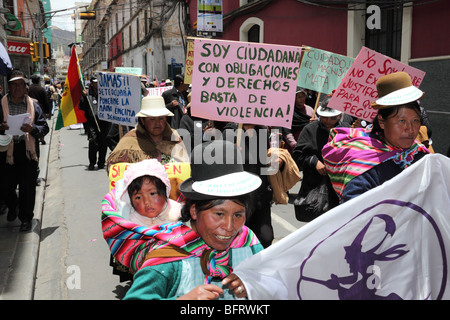 Aymara donna che indossa un abito tradizionale che porta un bambino in marcia di protesta per la giornata internazionale di non violenza contro le donne (25 novembre), la Paz, Bolivia Foto Stock