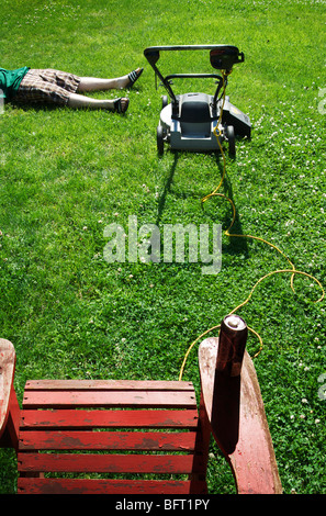 Ragazzo disteso accanto al tosaerba Foto Stock