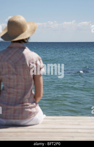 Donna seduta al fine del Dock Foto Stock