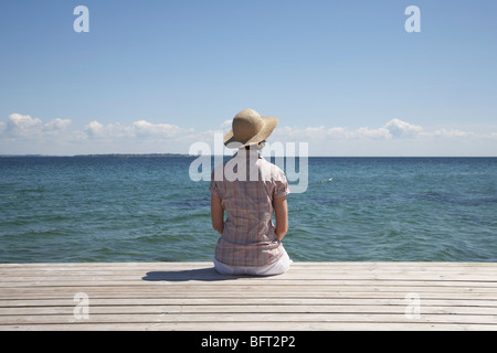 Donna seduta al fine del Dock Foto Stock