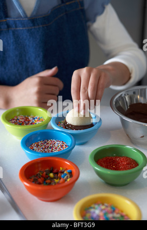 Donna frollini per immersione nel cioccolato e spruzza Foto Stock