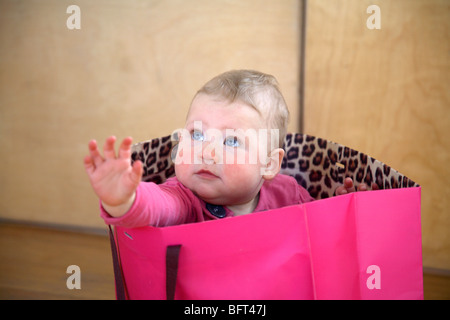 Baby ragazza seduta in una Rosa Shopping Bag Foto Stock