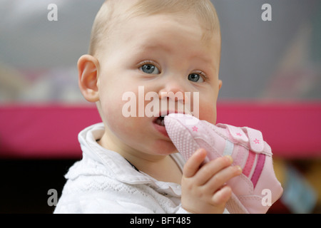 Baby girl masticare una scarpa Foto Stock