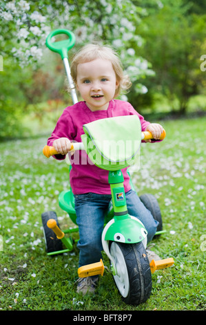 Bambina a cavallo di tre ruote moto Foto Stock