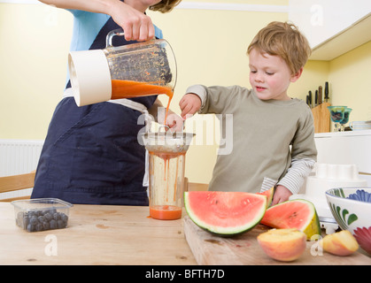 Ragazzo e la mamma rendendo frullati di frutta Foto Stock