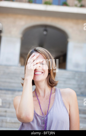 Donna che copre i suoi occhi sorridenti Foto Stock