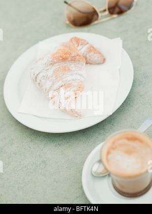 Croissant e caffè e occhiali da sole Foto Stock