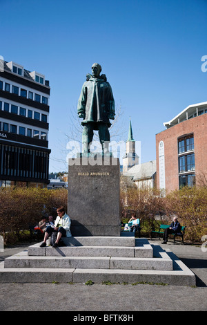 Statua di Roald Amundsen in Tromso Norvegia, donna seduta sulle scale e lettura. Foto Stock