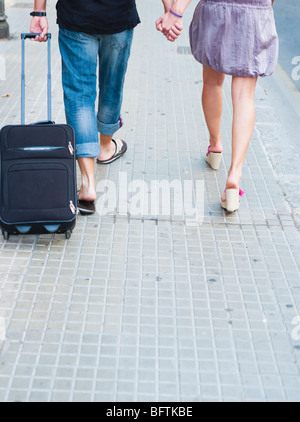 Coppia con trolley a piedi lungo la strada Foto Stock