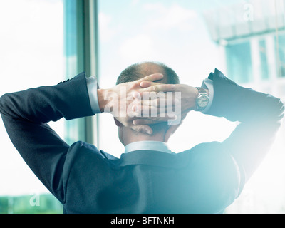 Uomo d'affari alla ricerca attraverso la finestra Foto Stock