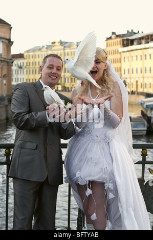 Felice giovane sposa giovane lasciare fuori i piccioni. Le colombe nelle loro mani iniziare a volare. Foto Stock