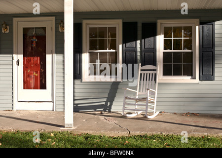 Rosso porta di entrata & incantevole portico anteriore con legno bianco sedia a dondolo vecchia clapboard grigie casa in autunno il giorno Montgomery New York Foto Stock