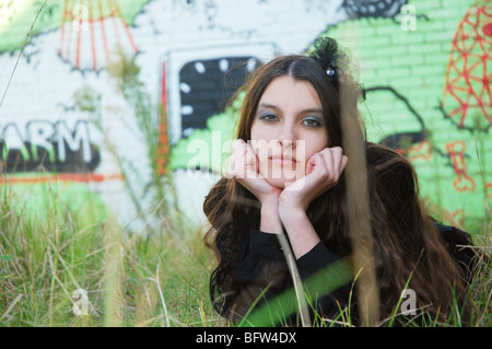Giovane donna in posa di fronte del muro di graffiti Foto Stock